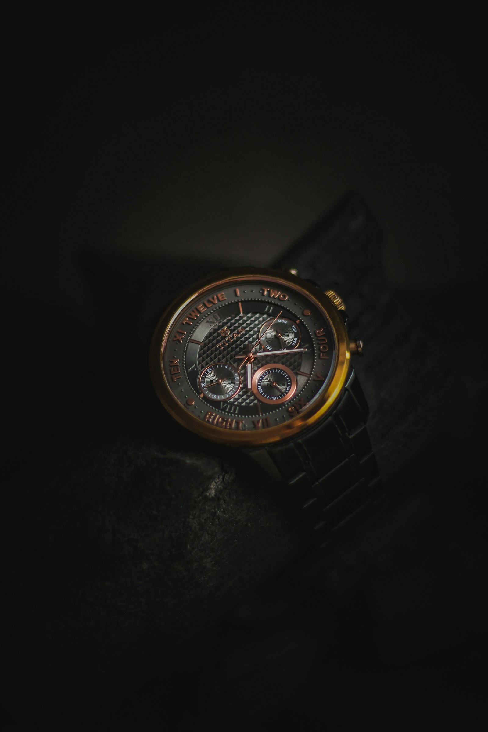 Black and gold watch on a dark textured surface